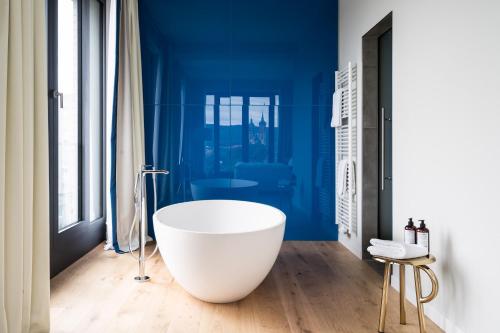 a bath tub in a bathroom with blue walls at FREIgeist Göttingen Innenstadt, A Member of Design Hotels in Göttingen