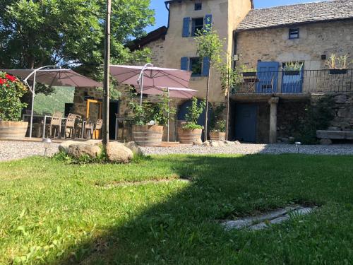 a yard with chairs and umbrellas in front of a house at Cal Xandera in Angoustrine