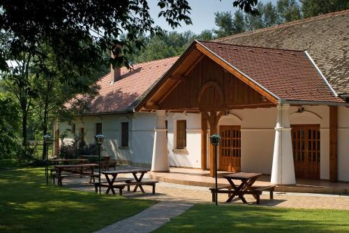a group of picnic tables in front of a building at Geréby Kúria Hotel és Lovasudvar in Lajosmizse