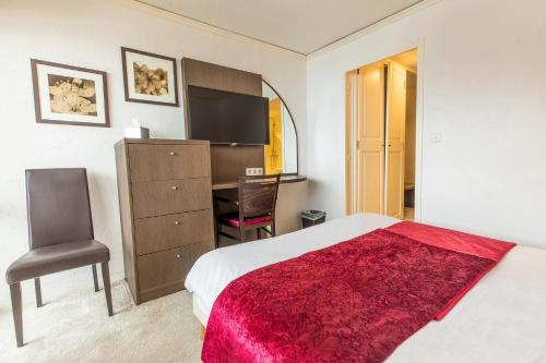 a bedroom with a bed and a desk and a chair at Madame Vacances Hôtel & Spa Le Mottaret in Méribel