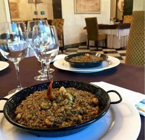 a table with two plates of food and wine glasses at Hotel Restaurante El Valles 4 ESTRELLAS in Briviesca