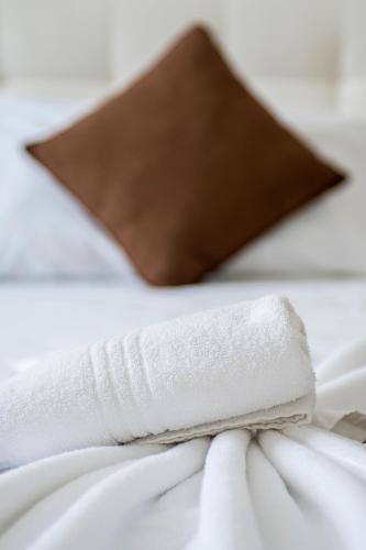 a white towel on a bed with a brown pillow at Luxury & Panorama Apartments in Budapest