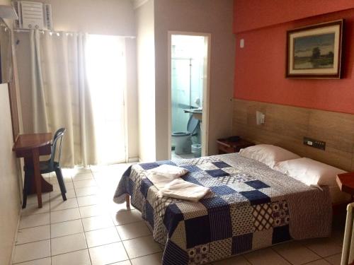 a room with a bed, table, and window at Hotel Marlin Azul in Vila Velha