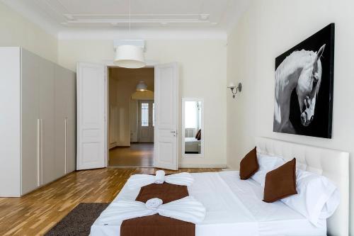 a bedroom with a white bed with a horse picture on the wall at Luxury & Panorama Apartments in Budapest