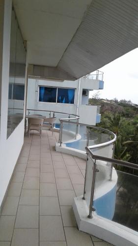 a balcony with tables and chairs on a building at Cowrie Shell Beach Apartments Official in Bamburi