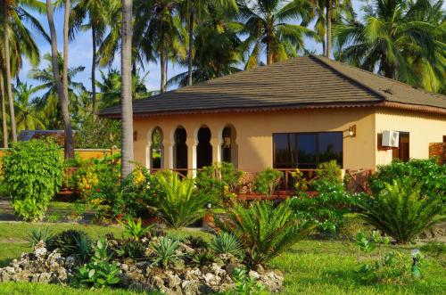 a small house with palm trees in a garden at The Sands Beach Resort in Bwejuu