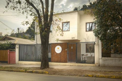 a white house with a gate and a tree at Casa Bellavista Hotel in Santiago