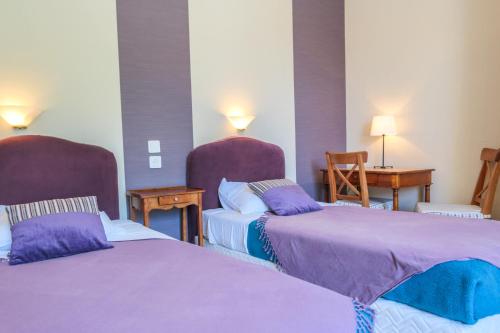 a hotel room with two beds with purple sheets at Résidence du Château de Bégué in Cazaubon