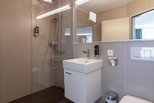 ein weißes Bad mit einem Waschbecken und einer Dusche in der Unterkunft Trip Inn Zurich Hotel in Zürich