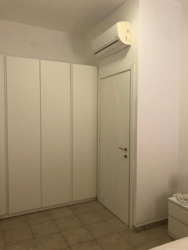 an empty room with white cabinets and a door at Case sul mare in Palau