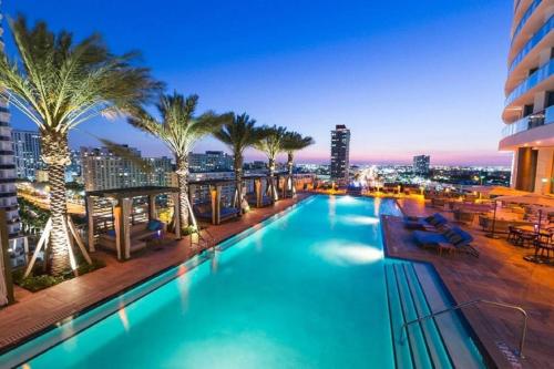 a pool on the roof of a building with palm trees at Rent in LYFE Resort in Hollywood