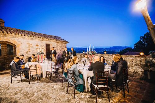 Un groupe de personnes assises à des tables lors d'un événement dans l'établissement Castello Di Giomici, à Valfabbrica
