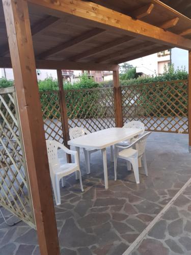 a white table and chairs under a wooden pergola at Il Giardino degli Ulivi in Rapolano Terme