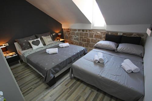 - une chambre avec 2 lits et un mur en pierre dans l'établissement Apartman Tara, à Split