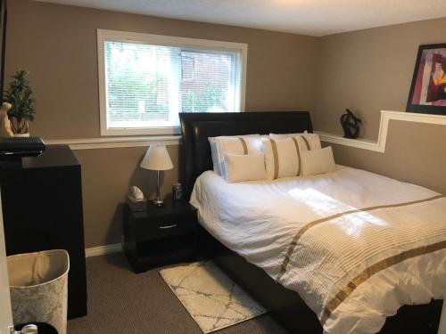 a bedroom with a bed with white sheets and a window at Cozy and modern 3 bedroom in central location! in Victoria