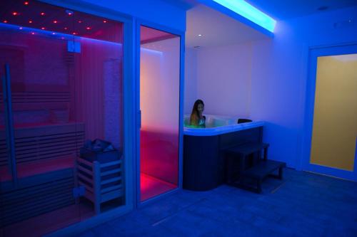 a woman in a bathroom with purple and pink lights at Vento di Sicilia in Siracusa