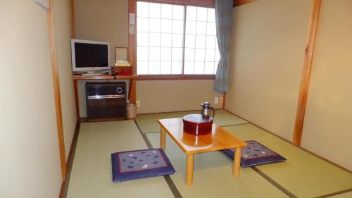 a living room with a table and a tv at Minshuku Iwatakan in Takayama