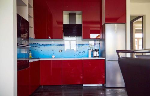 a kitchen with red cabinets and blue walls at Blue Door Apartment Ground Floor in Augustów