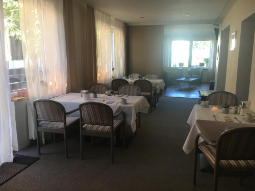 a dining room with white tables and chairs at Pension Richter in Nienhagen