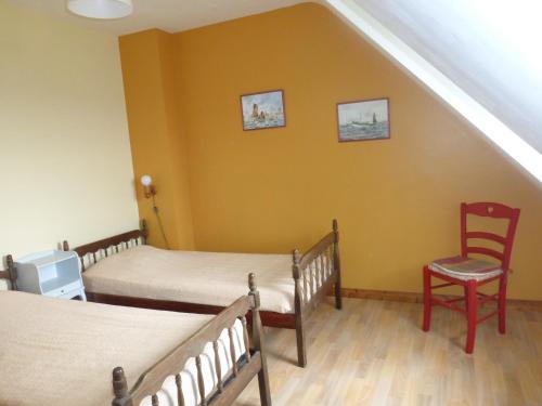 Cette chambre aux murs jaunes comprend 2 lits et une chaise. dans l'établissement les volets bleus, 100m de la plage, à Camaret-sur-Mer