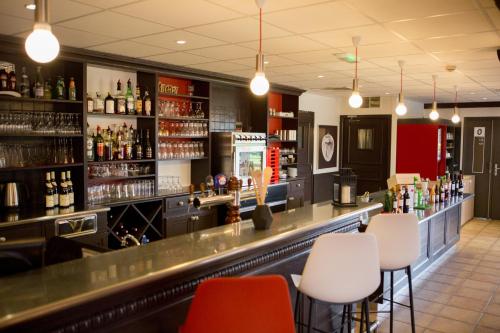 a bar with white chairs and bottles of alcohol at ibis Cherbourg La Glacerie in Cherbourg en Cotentin
