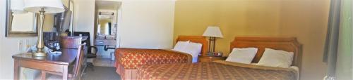 a bedroom with two beds and a desk and a lamp at Executive Inn Mojave in Mojave