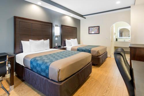 a hotel room with two beds and a desk at Econo Lodge Inn & Suites Houston Willowbrook in Houston
