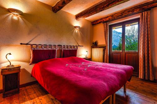 a bedroom with a large red bed with a window at Agriturismo il Fiocco in Cesana Torinese