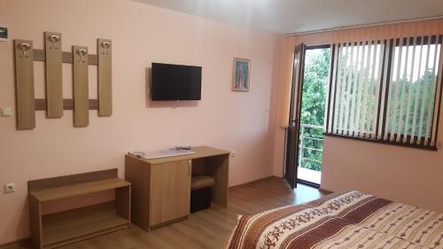 a bedroom with a bed and a television on the wall at Chilingirovata Kashta in Pavel Banya