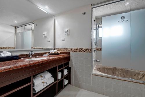 a bathroom with a shower and a sink and a tub at El Cid La Ceiba Beach in Cozumel