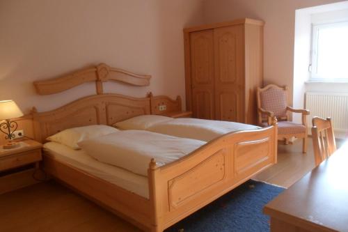 a bedroom with a large wooden bed and a chair at Hotel Badstube in Otterberg