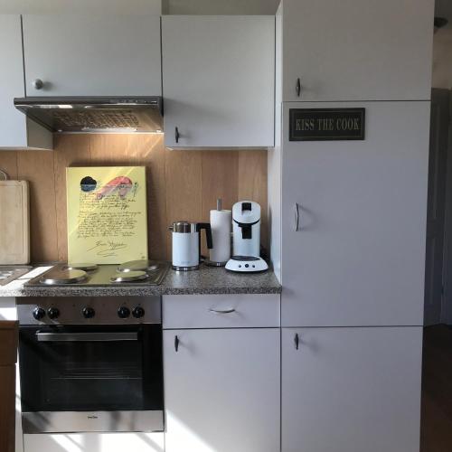 a kitchen with white cabinets and a stove top oven at Hummerstübchen Morsum in Morsum