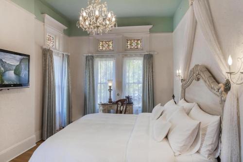 a bedroom with a white bed with pillows and a chandelier at Patterson Inn in Denver
