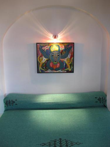 a painting on a wall above a green bench at Dar Al Bahar in Essaouira