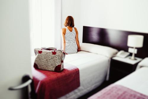 a woman sitting on a bed in a hotel room at Hotel Madrid de Sevilla by SHS in Seville