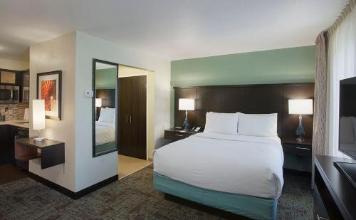 a hotel room with a large bed and a mirror at Staybridge Suites Fayetteville by IHG in Fayetteville
