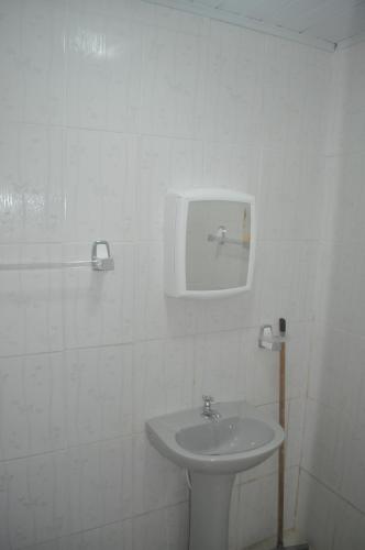 a white bathroom with a sink and a mirror at Sitiopousada. " Os Tres " in Camaçari