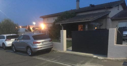 Deux voitures garées sur un parking en face d'une maison dans l'établissement Chambre dans une villa, à Beaupuy