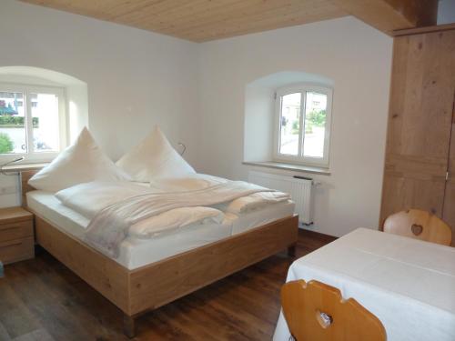 a white bedroom with a bed and two windows at Ferienwohnung zum Dorfwirt in Riedenburg
