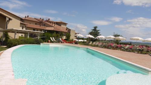 a large swimming pool with chairs and umbrellas at Hotel Borgo Di Cortefreda in Tavarnelle Val di Pesa