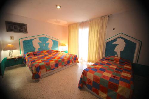 a bedroom with two beds and a window at Hotel Carrillos Cancun in Cancún