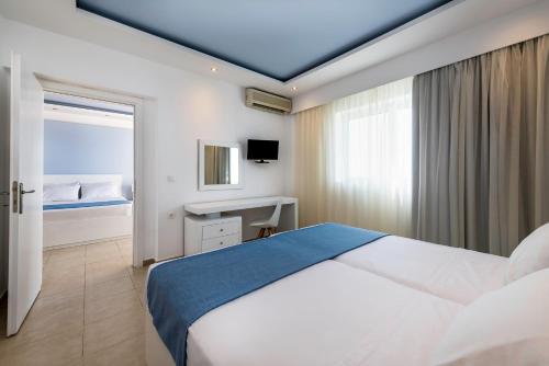 a bedroom with a bed and a desk and a window at Gaia Royal in Mastichari