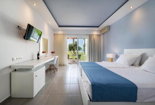 a bedroom with a bed and a desk and a television at Gaia Royal in Mastichari