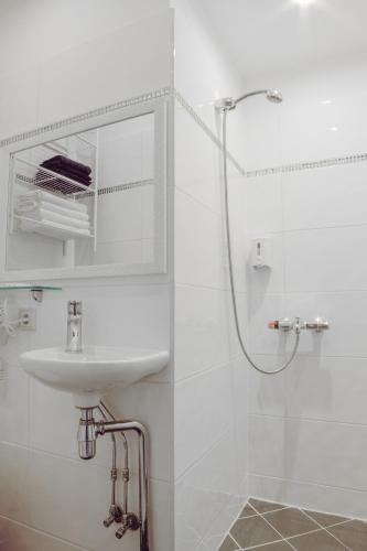 a white bathroom with a sink and a shower at Vallery Guest House in Bigauņciems