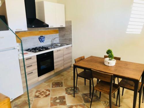 cocina con mesa de madera con sillas y fregadero en Simone Home, en Roccella Ionica