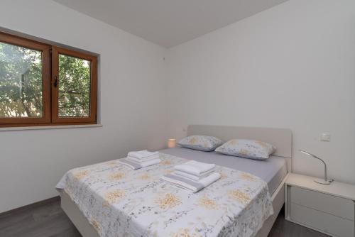 ein weißes Schlafzimmer mit einem Bett mit Kissen und einem Fenster in der Unterkunft Kiwi in Trogir
