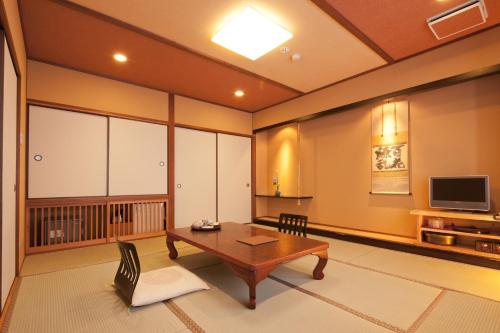 a living room with a table and a tv at Ryokan Oomuraya in Ureshino