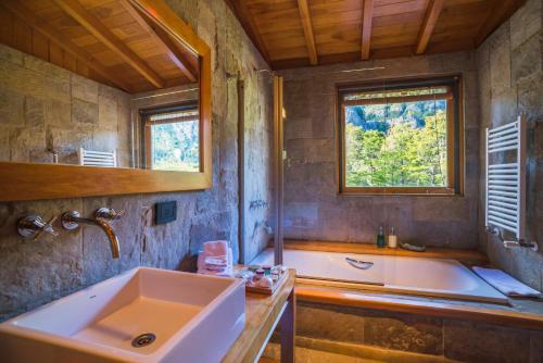 baño grande con bañera y lavamanos en Rio Hermoso Hotel De Montaña en San Martín de los Andes