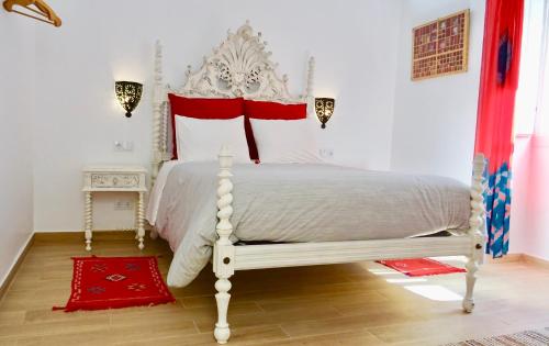 um quarto com uma cama branca e almofadas vermelhas em Casinhas da Ajuda nº 29 em Lisboa