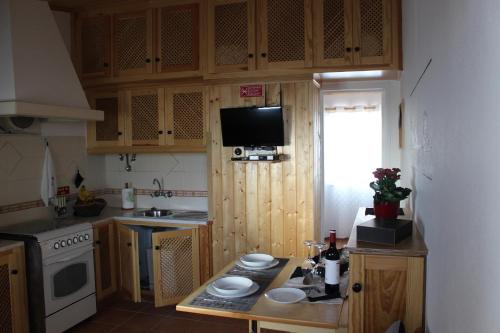 a kitchen with wooden cabinets and a table with plates on it at SigmaApartment in Zambujeira do Mar